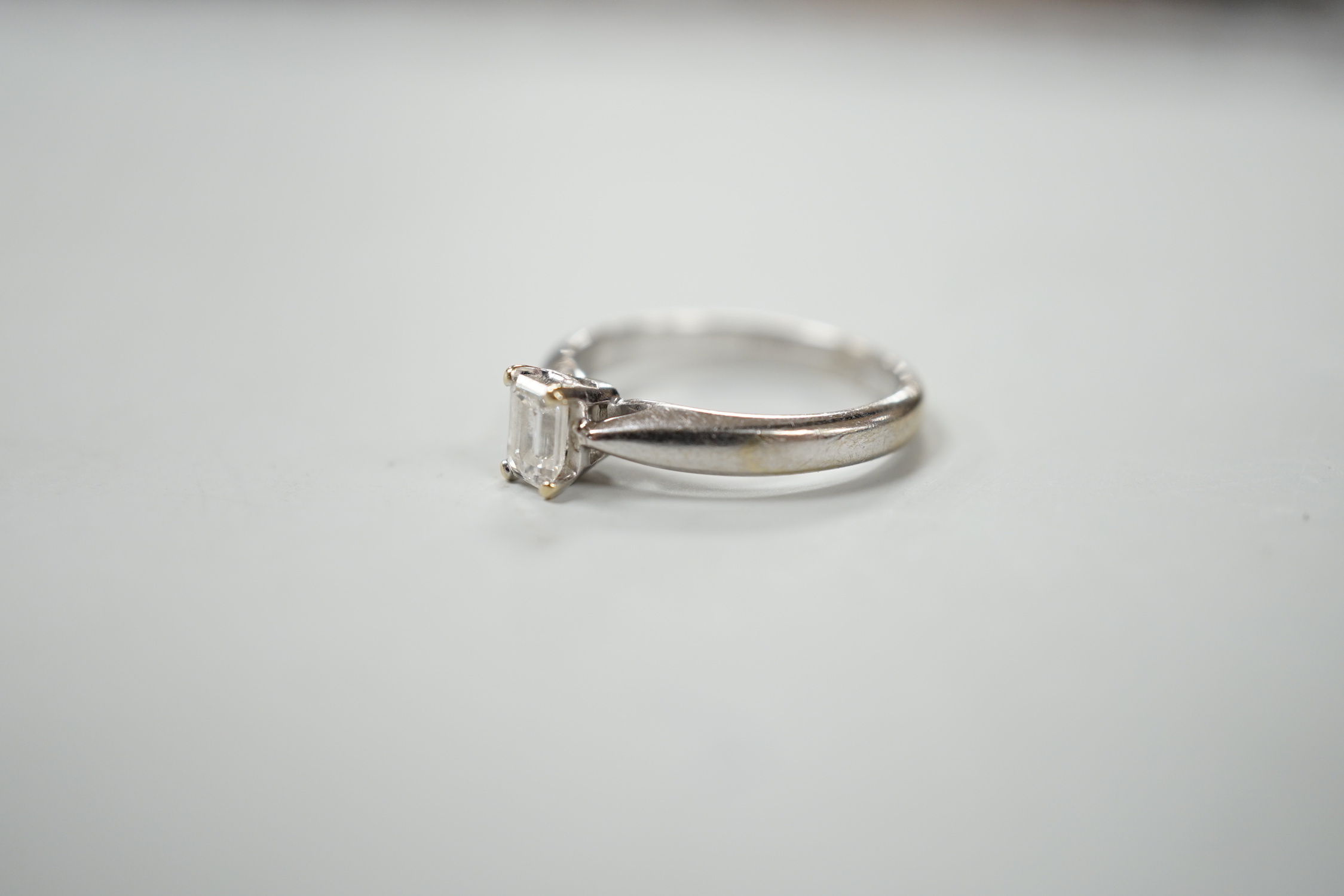 A 750 white metal and solitaire emerald cut diamond ring, size J/k, gross weight 2.9 grams.